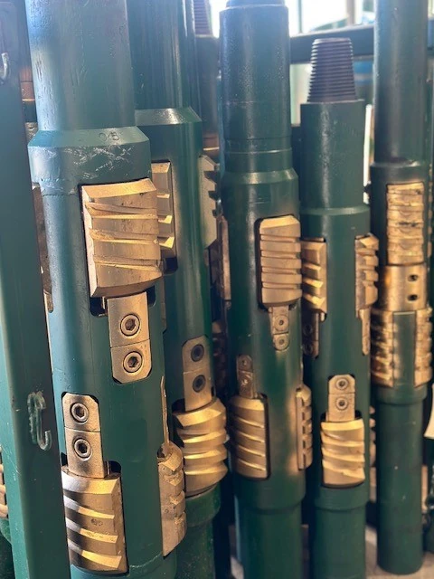 Casing scrapers with brass scraper blocks on green bodies, standing in a shop rack